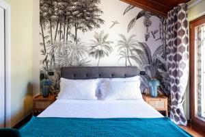 a bedroom with a bed with a tropical wallpaper at Pavean Suites Frattaminore in Frattaminore