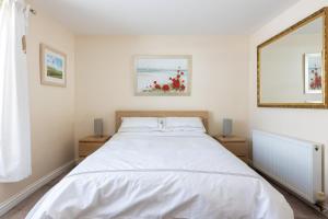 a bedroom with a bed with white sheets and a mirror at Mabel Cottage in Torquay