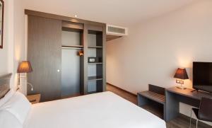 a bedroom with a bed and a desk and a television at Sercotel Plaza Feria in Zaragoza