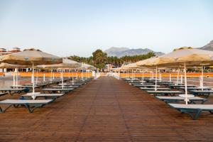 a row of lounge chairs and umbrellas on a beach at AQI Hydros Club in Kemer
