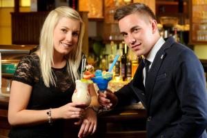 Un uomo e una donna in piedi al bar con un drink di Hotel Alpenhof Superior a Zauchensee