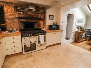 a kitchen with a stove and a stone wall at Garretts in Torpoint