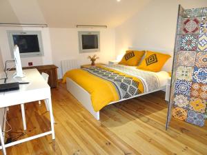 富瓦的住宿－Agréable maison au centre historique de Foix avec garage，一间卧室配有一张带黄床单的床和一张书桌。