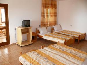 a hotel room with three beds and a tv at Къща за гости Костови in Byala
