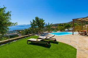 een zwembad met 2 ligstoelen op het gras bij Elounda Blue Waves in Elounda