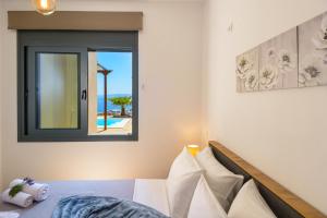 een slaapkamer met een bed en uitzicht op de oceaan bij Elounda Blue Waves in Elounda +30 foto's