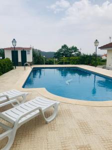 a swimming pool with two lounge chairs next to it at Monte das Cerejas in Montes da Senhora