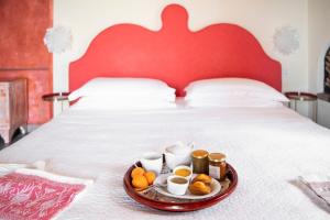 a tray with cups and oranges on a bed at Villa Paggi Country House in Carasco