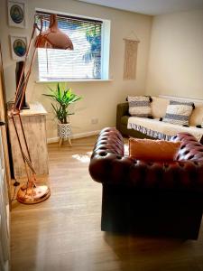 a living room with a leather couch and a window at Aqua Shack at Pure Shores Retreats in Newquay