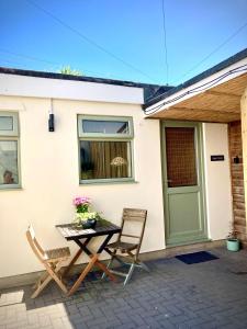 uma mesa e cadeiras fora de uma casa com uma porta em Aqua Shack at Pure Shores Retreats em Newquay