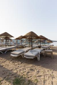 a group of lounge chairs and umbrellas on a beach at Costa Bitezhan Hotel - All Inclusive in Bitez