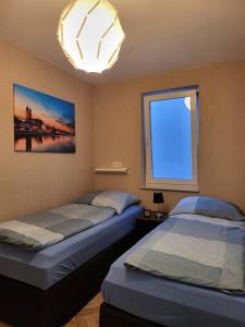 two beds in a room with a window at Gemütliche Dachwohnung mit kleiner oder großer Dachterrasse nebeneinander in Wolmirstedt