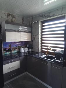 eine Küche mit schwarzen Schränken, einem Waschbecken und einem Fenster in der Unterkunft Willa Aurelcia in Świnoujście