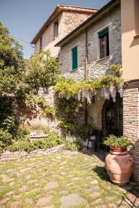 una casa in pietra con un grande vaso di fronte di Social Garden a Calci