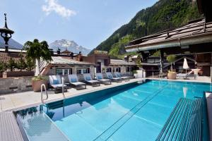 einen großen Pool mit Stühlen und einem Berg in der Unterkunft Hotel Neue Post in Mayrhofen