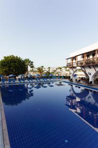 a large swimming pool with chairs and umbrellas at Costa Bitezhan Hotel - All Inclusive in Bitez