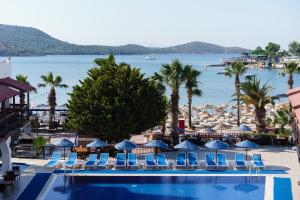 a swimming pool with chairs and umbrellas and a beach at Costa Bitezhan Hotel - All Inclusive in Bitez