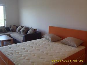 a large bed in a room with a couch at Apartmani Vukovic in Tivat