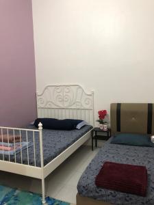 1 dormitorio con 2 camas y una mesa con flores en Ina Homestay Jerantut, en Jerantut