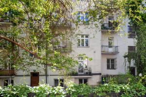 un edificio alto de color blanco con ventanas y árboles en Królewska Apartments en Cracovia