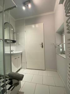 a white bathroom with a shower and a sink at Pokoje w Orłowie in Gdynia