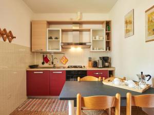 una cocina con armarios rojos y una mesa con sillas. en Apartment Punto Lago by Interhome, en Verceia