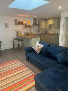 uma sala de estar com um sofá azul e uma cozinha em Beach, hills, food, scenic walks-The Kelp house. em Peacehaven