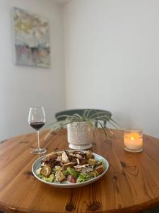 um prato de comida numa mesa de madeira com um copo de vinho em Beach, hills, food, scenic walks-The Kelp house. em Peacehaven