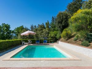 uma piscina com um guarda-sol e cadeiras e uma mesa em Holiday Home Il Felciaio by Interhome em Sassa