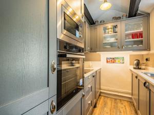 eine Küche mit Küchengeräten aus Edelstahl und Holzböden in der Unterkunft 2 Sea View Cottage in Pwllheli