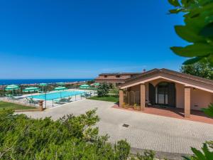a building with a pool and the ocean in the background at Holiday Home Il Corbezzolo-1 by Interhome in San Vincenzo