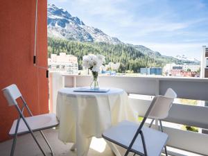 a table with a vase of flowers on a balcony at Apartment Appartmenthaus Skyline 309 by Interhome in St. Moritz