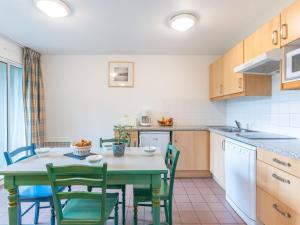 una cocina con mesa con sillas verdes y una cocina con fregadero en Apartment Village Cheval Spa Résidences-4 by Interhome, en Lacanau-Océan