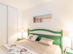 a bedroom with a green bed with two pillows at Apartment Village Cheval Spa Résidences-4 by Interhome in Lacanau-Océan +26 photos