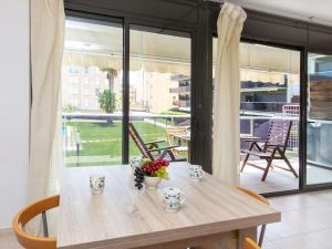 una mesa de madera con flores en una habitación con ventanas en Apartment El Jardi del Mar, en Sant Antoni de Calonge