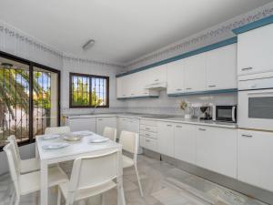 ミハス・コスタにあるVilla Querida by Interhomeの白いキャビネット、テーブルと椅子付きのキッチンが備わります。