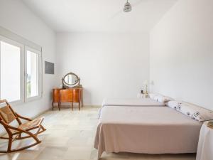 a white bedroom with two beds and a chair at Holiday Home Finca La Veleta by Interhome in Los Gallardos