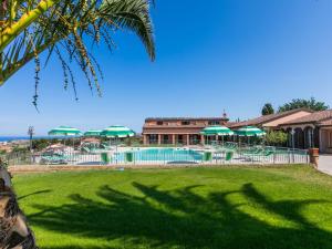 サン·ヴィンチェンツォにあるHoliday Home Il Corbezzolo-3 by Interhomeの緑のパラソルとリゾート付きのプール