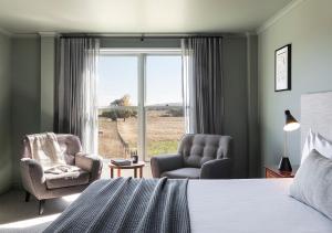 a bedroom with a bed and two chairs and a window at Cleveland Estate in Lancefield