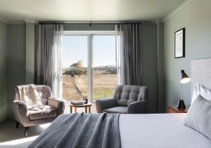 a bedroom with a bed and two chairs and a window at Cleveland Estate in Lance Field