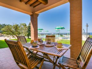 einen Holztisch mit zwei Stühlen auf einer Terrasse in der Unterkunft Holiday Home Il Corbezzolo-2 by Interhome in San Vincenzo