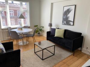 uma sala de estar com um sofá preto e uma mesa em Modern 1-bedroom apartment in charming Østerbro em Copenhague