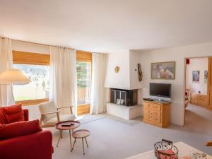 a living room with a red couch and a television at Apartment Chesa Pra d`Sura 217-10 by Interhome in Maloja