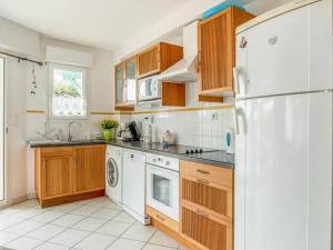 ミミザン・プラージュにあるHoliday Home Le Hameau des Pêcheurs 5-1 by Interhomeのキッチン(木製キャビネット、白い冷蔵庫付)