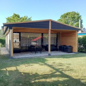 a wooden pavilion with a table in a yard at Horrelshoogte 15, cozy house with private garden near the beach - not for companies in Ouddorp