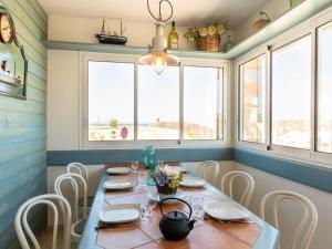 a dining room with a table and chairs and windows at Holiday Home Villa Marine by Interhome in Mimizan-Plage +28 photos