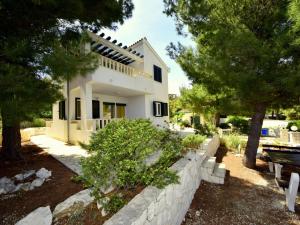 a white house with trees and a retaining wall at Holiday Home Željko by Interhome in Zaglavice