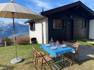 a table with chairs and an umbrella in front of a house at Chalet Chalets Tsamandon by Interhome in Nendaz