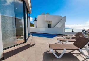 un patio con sillas y mesas en la azotea en Villa Torre Paraíso, en Torrox