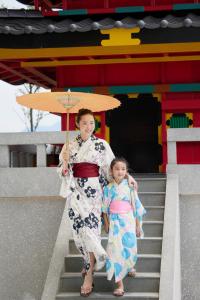 una mujer y un niño bajando las escaleras sosteniendo un paraguas en Da Nang - Mikazuki Japanese Resorts & Spa, en Da Nang